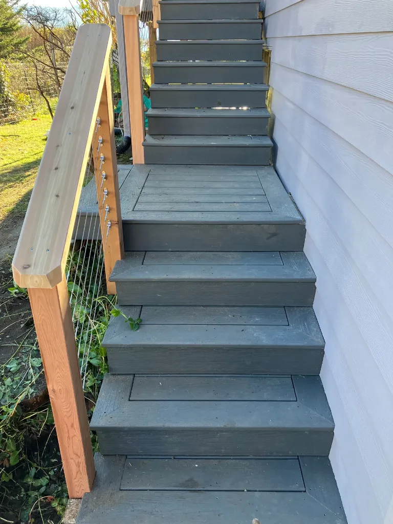 Exterior deck stairs with horizontal cable railing and natural timber handrail